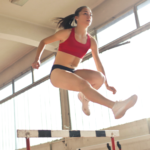 woman jumping over a hurdle