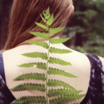 woman standing with her back to the camera holding a leaf behind her